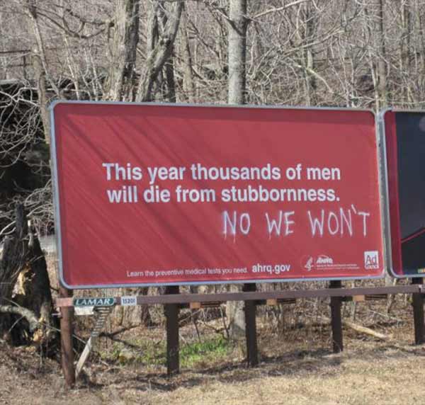 Sign: "This year thousands of men will die from stubbornness." Grafitti: "NO WE WON'T"